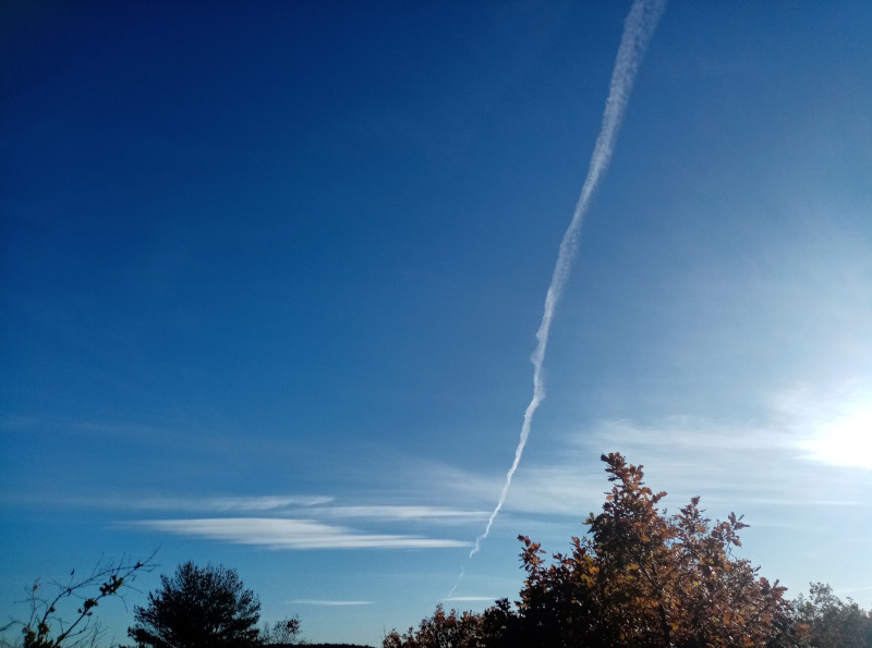 Traînées laissées
        par un avion dans un ciel bleu avec quelques nuages